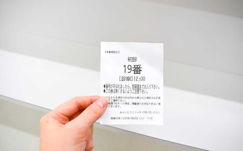 来院・受付の受付後に番号札が渡される画像